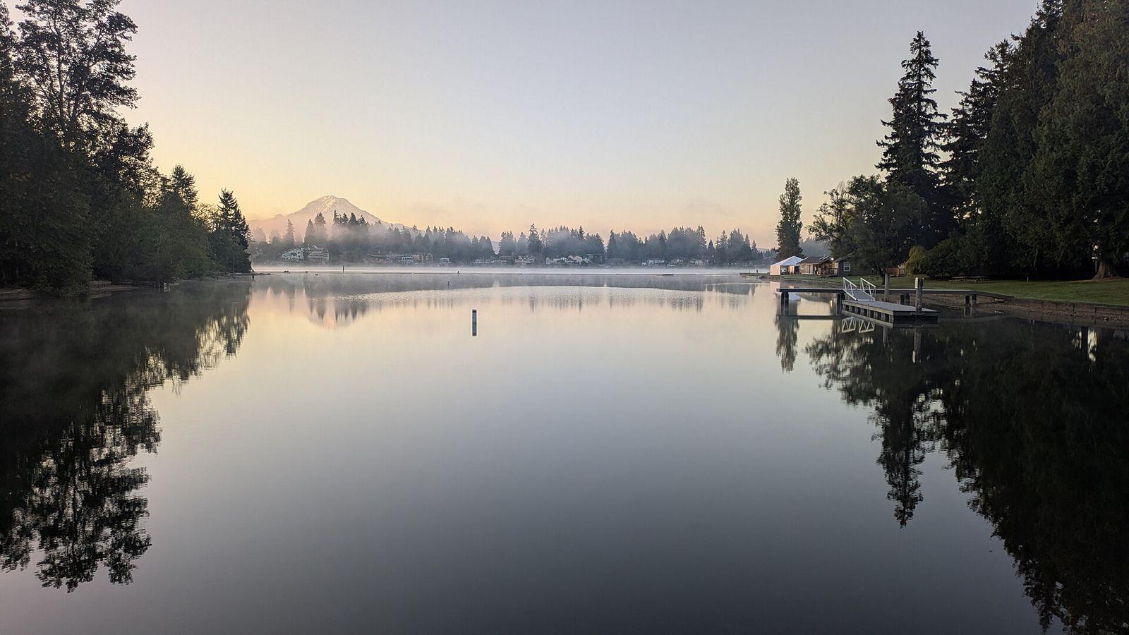 Calm Lake Tapps at dawn with docks along the shore and Mount Rainier on the horizon