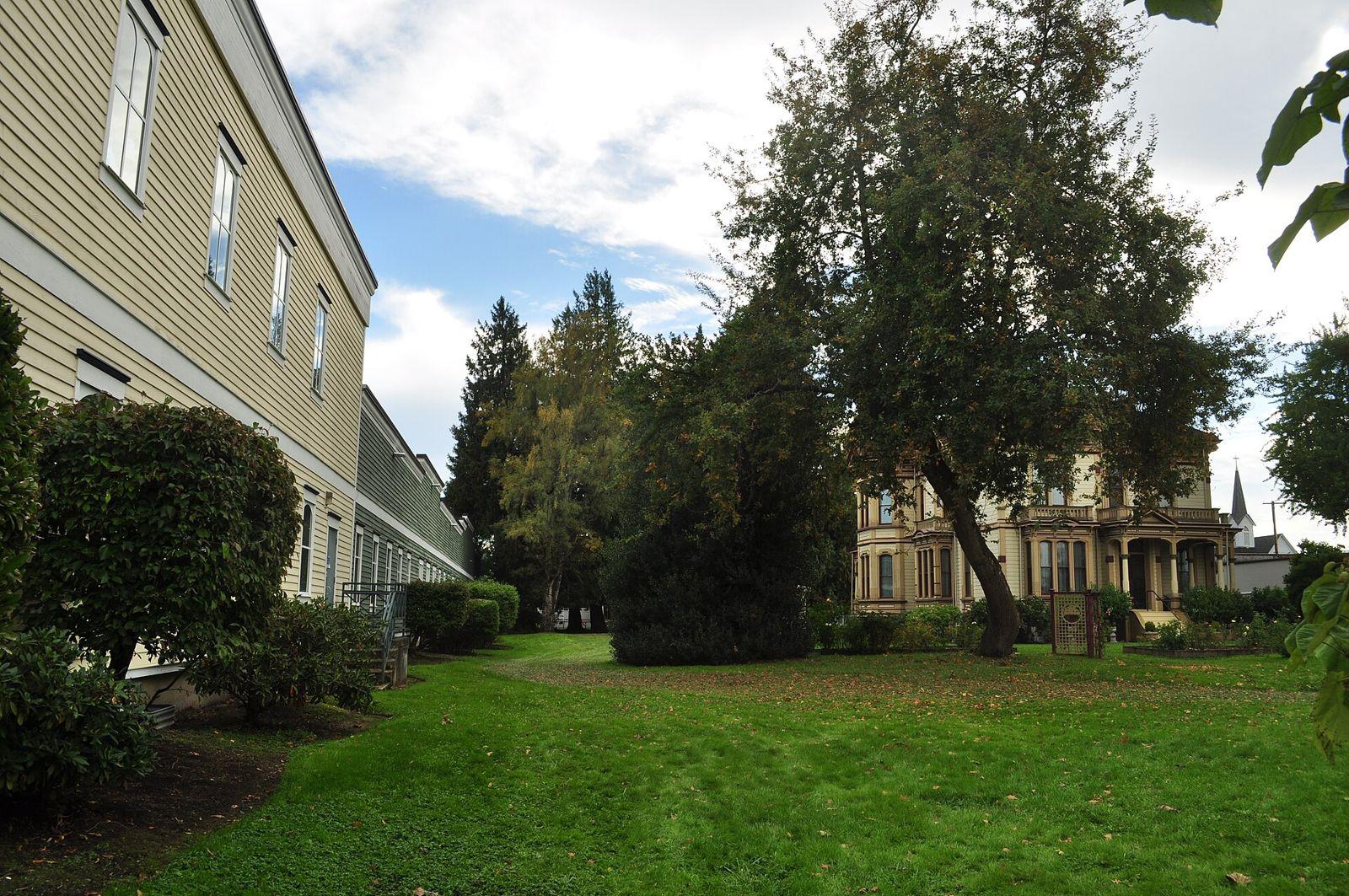 Historic Ezra Meeker Mansion surrounded by lawn and trees in Puyallup on a bright day