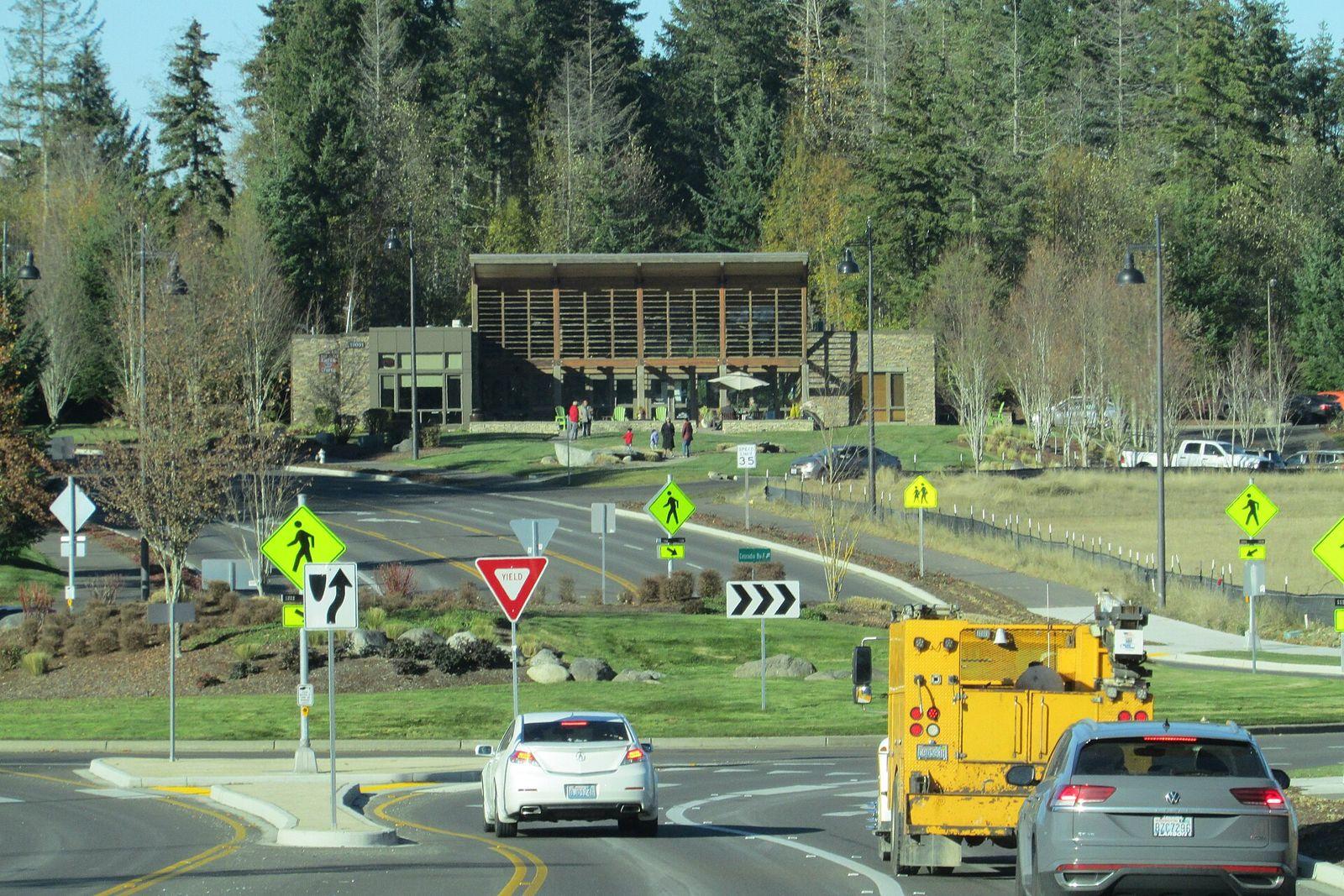 The Post at Tehaleh with a roundabout, newer buildings, and evergreen trees on a sunny day